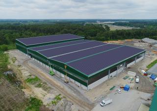 Vue aérienne d'un vaste bâtiment industriel ou agricole aux toits couverts de panneaux solaires